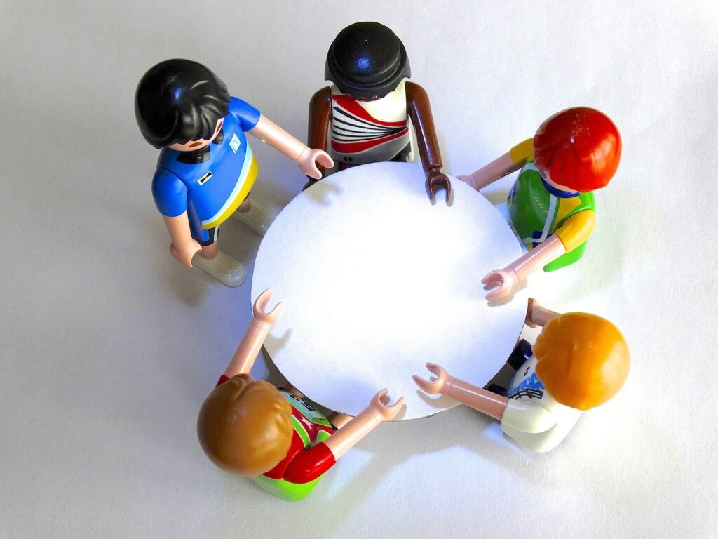 Das Bild zeigt eine Gruppe Playmobilmännchen an einem Tisch. Blockaden lösen | Kinder- und Jugendcoaching
